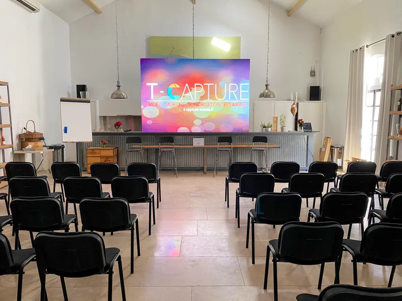 LED screen displaying T-CAPTURE branding in a seated venue